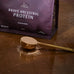 Brave Ancestral Protein packaging with a scoop of protein powder on a wooden surface