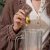 Person pouring Brave Ancestral Protein from a small container into a glass pitcher.