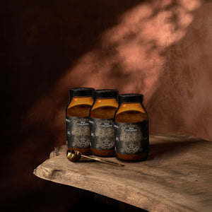 Three jars of ‘True Collagen' on a wooden surface with a warm brown background